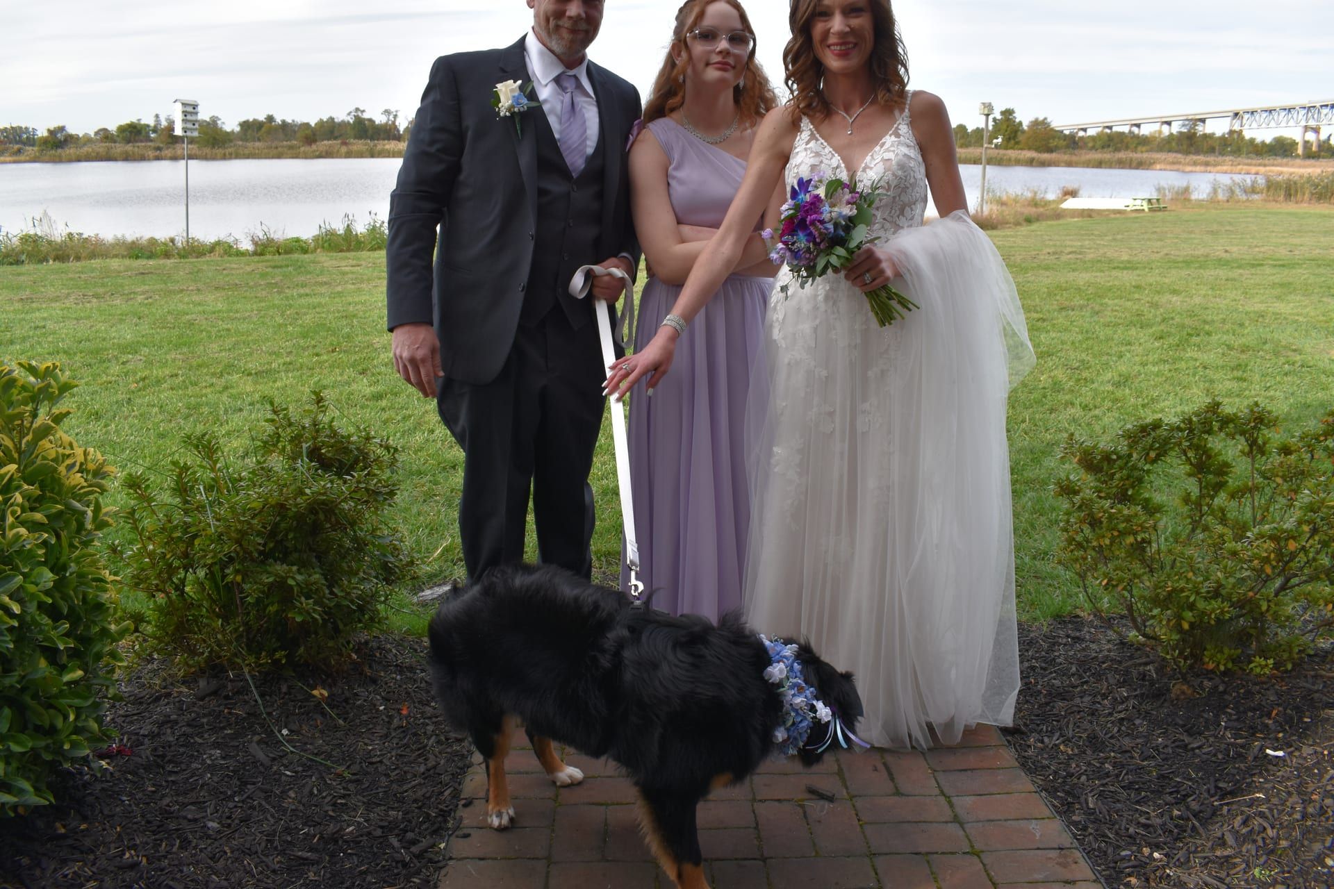 Wedding couple with bridesmaid and dog by the lake