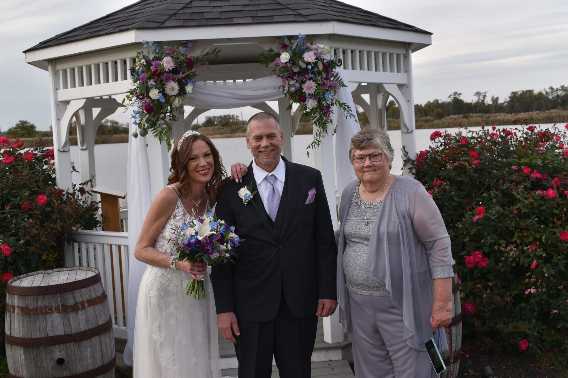 Couple with guest at flower-adorned gazebo